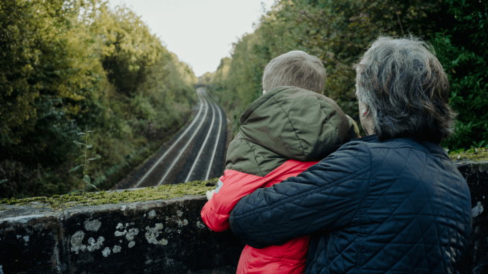 Young boy and grandfather looking at the railway